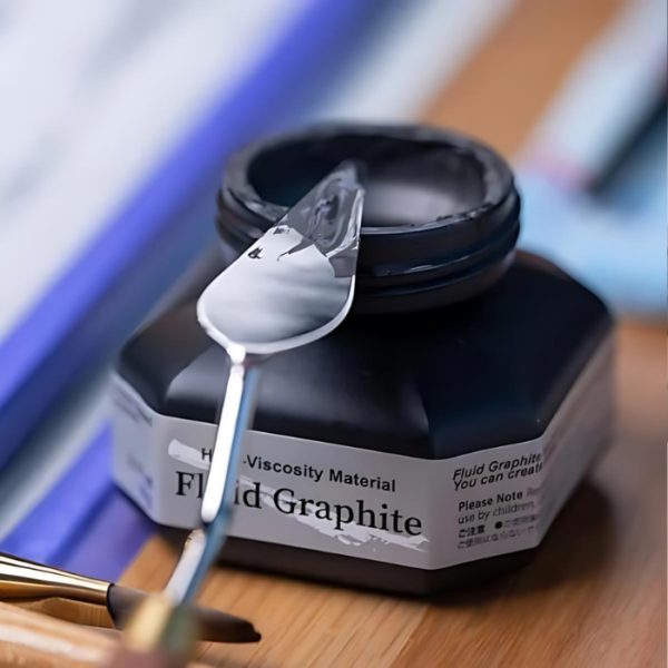 A close up of an open bottle of Kuretake ZIG Fluid Graphite 60ml with a metal palette knife leaning on the top of the bottle. The bottle is a clear plastic and you can see the black fluid through the bottle. There is a label around the body of the bottle with the product name and details printed on it.