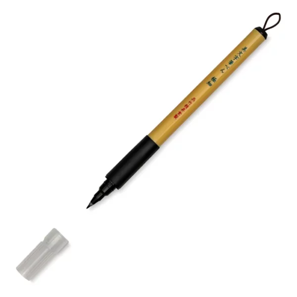 a single kuretake bimoji fude pen is in the center of the image at an angle. sitting diagonally across the screen from tip on the left bottom to the end on the top right corners respectively. it has a brown handle with a black top and a black bottom with a string on it. the nib is visable and the cap is sitting infront of it. on a white background