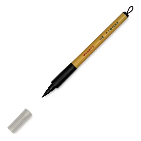 a single kuretake bimoji fude pen is in the center of the image at an angle. sitting diagonally across the screen from tip on the left bottom to the end on the top right corners respectively. it has a brown handle with a black top and a black bottom with a string on it. the nib is visable and the cap is sitting infront of it. on a white background