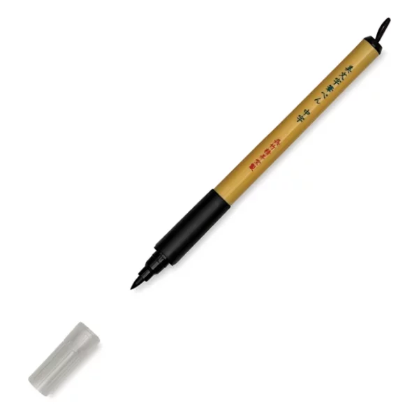 a single kuretake bimoji fude pen is in the center of the image at an angle. sitting diagonally across the screen from tip on the left bottom to the end on the top right corners respectively. it has a brown handle with a black top and a black bottom with a string on it. the nib is visable and the cap is sitting infront of it. on a white background