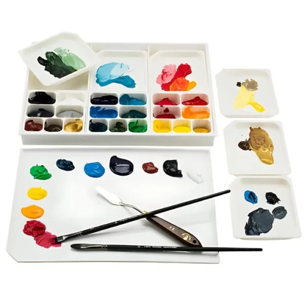 An open Acryl-a-Miser Palette is shown horizontally across the center of the frame. The palette is made of white plastic and each well is filled with a different colour paint. There are two paint brushes and a palette knife laying on the bottom of the palette. The image is center of the frame and on a white background.