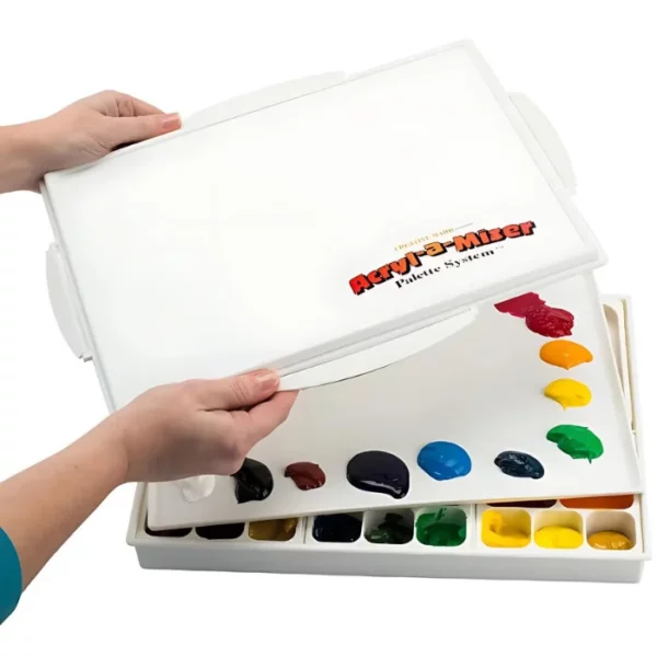 A persons hands are seen coming in from the left hand side of the frame, holding the Acryl-a-Miser Palette lid over the palette base. The lid has the Acryl-a-Miser logo printed in the bottom right hand corner. There is paint in the wells in the bottom of the palette. On a white background.