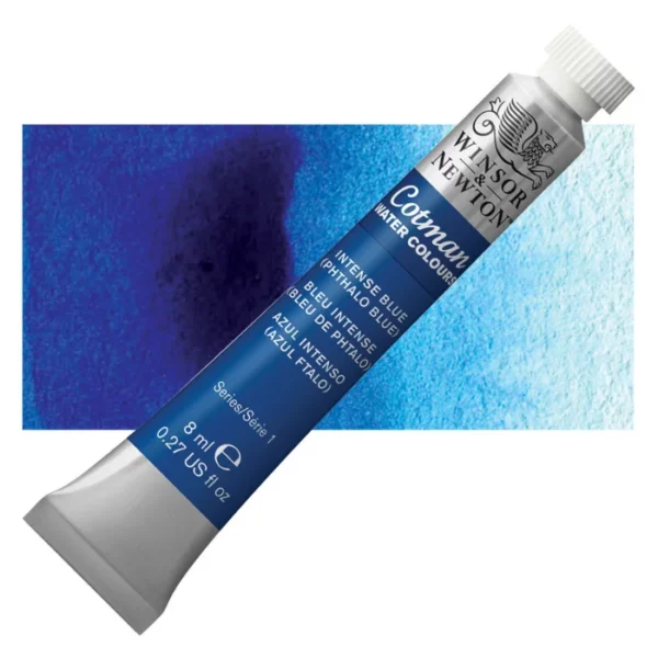 A single Intense Phthalo Blue Winsor and Newton Cotman Watercolour 8ml Tube is shown diagonally across the frame. The back of the tube is facing the bottom left hand corner of the frame and the lid of the tube is facing the top, right hand corner of the frame. The tube is silver and the Winsor and Newton logo is printed at the top of the tube. There is a blue band below the logo and the words 'Cotman Watercolour' are printed on the blue band in white. Then there is a large colour band around the base of the tube that denotes the colour of the paint. The tube colour and paint properties are indicated on this colour band in black text. The tube has a white, plastic screw on cap. There is a rectangular colour swatch behind the tube that shows how the colour works on a gradient scale. The entire image is center of the frame and on a white background.