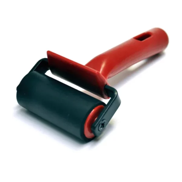 A single Prime Art Ink Roller is shown in the center of the frame diagonally across the frame. The roller head is facing the bottom left hand corner of the frame and the handle is facing the top right hand corner of the frame. The handle is made of a red plastic and the rubber roller is black in colour. The image is center of the frame and on a white background.