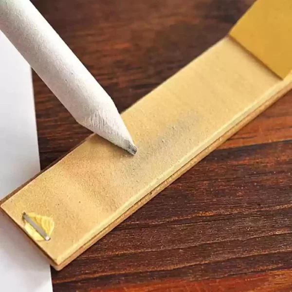 A close up of a Prime Art Paper Stump being sharpened on a sanding block. The stump is light grey in colour. There is a wooden surface in the background.