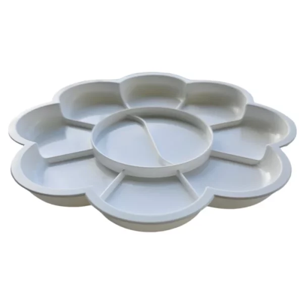 A Prime Art Plastic Palette 8 Well Flower is shown in the center of the frame. The palette is shown from a side on view. The palette is a round flower shape and made of a white plastic. It has 8 wells to hold paint. The image is center of the frame and on a white background.