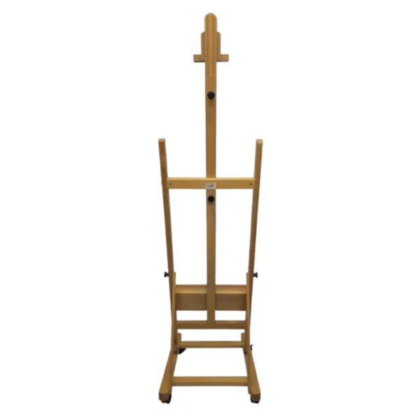 A single Prime Art Wooden Studio H-Frame Beech Easel with Wheels is shown in the center of the frame. It is a view of the back of the easel. The easel is made of a light beech wood and the castor wheels are black plastic. On a white background.