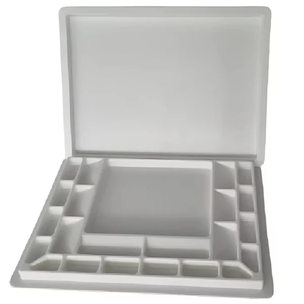 A Sterling Edwards Big Brush Palette is shown in the center of the frame, with the hinged lid open towards the top of the frame. The palette is white plastic and has 14 wells of different sizes. The image is center of the frame and on a white background.