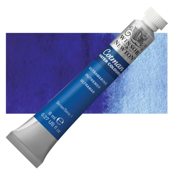 A single Ultramarine Winsor and Newton Cotman Watercolour 8ml Tube is shown diagonally across the frame. The back of the tube is facing the bottom left hand corner of the frame and the lid of the tube is facing the top, right hand corner of the frame. The tube is silver and the Winsor and Newton logo is printed at the top of the tube. There is a blue band below the logo and the words 'Cotman Watercolour' are printed on the blue band in white. Then there is a large colour band around the base of the tube that denotes the colour of the paint. The tube colour and paint properties are indicated on this colour band in black text. The tube has a white, plastic screw on cap. There is a rectangular colour swatch behind the tube that shows how the colour works on a gradient scale. The entire image is center of the frame and on a white background.