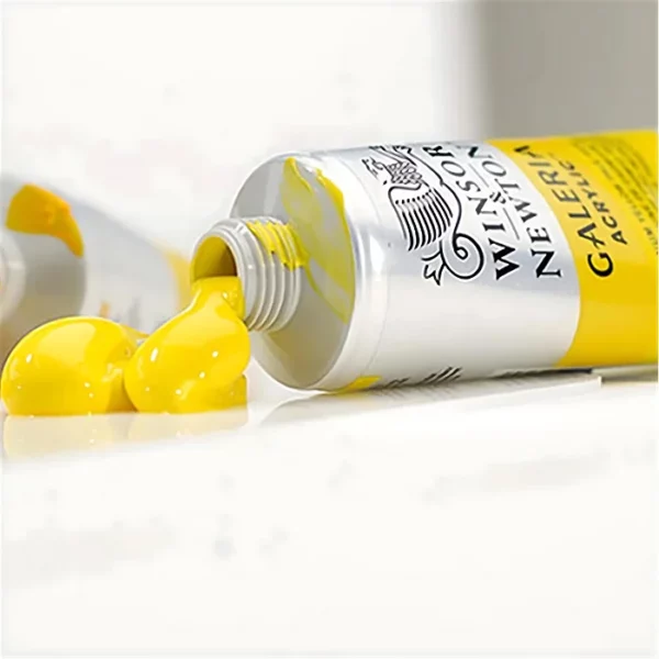 A tube of yellow Winsor and Newton Galeria Acrylic Paint is seen coming in from the right hand side of the frame. The cap is off and the yellow paint is coming out of the tube. The image is cut off by the frame.