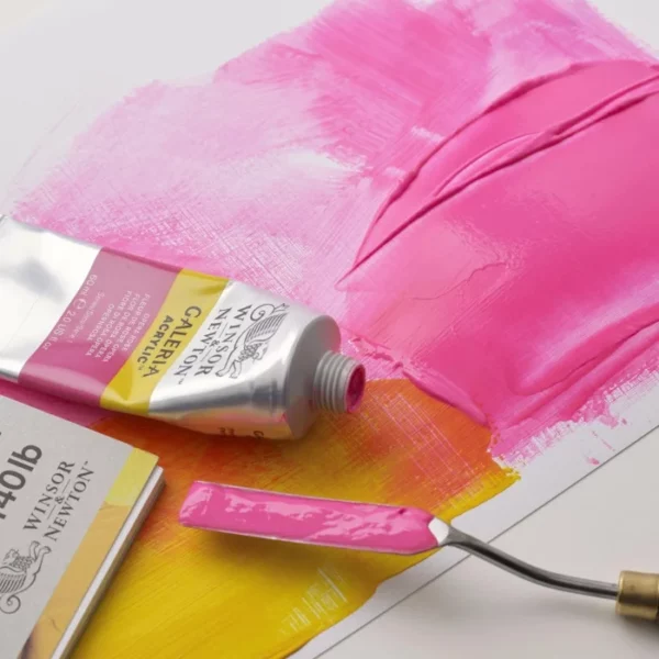 A close up image of some pink Winsor and Newton Galeria Acrylic Paint being applied to a surface using a palette knife.