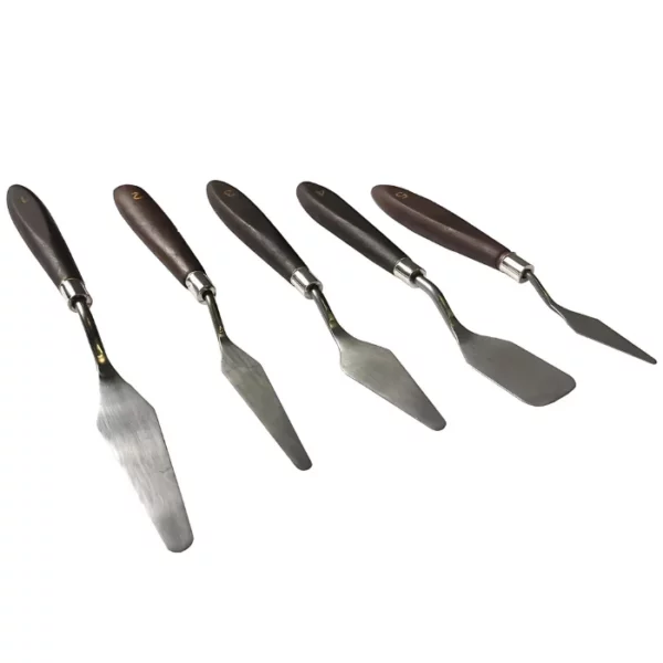 Loose palette knives from the Pro Art Steel Palette Knife Set are seen, fanned out in the center of the frame. The knives have wooden handles and metal blades. Each knife has a different shaped metal blade. On a white background.