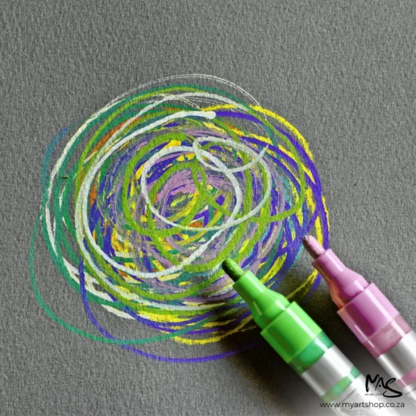 A close up of 2 marker pens in green and pink applying some ink in circles to a sheet of Fabriano Cromia Paper. The image is cut off by the frame. The paper is dark grey.
