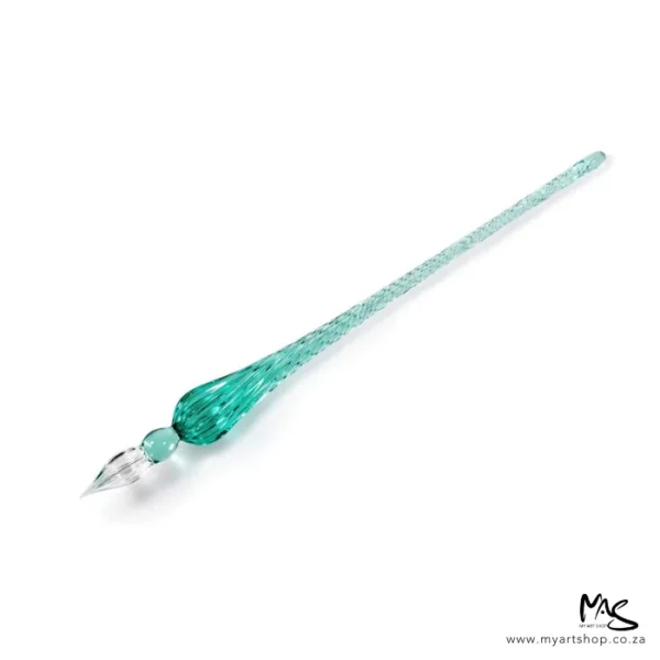A single Glass Dipping Pen is seen laying diagonally across the frame, with the end of the pen facing the top right hand corner and the nib facing the bottom left hand corner of the frame. The pen is green glass and is on a white background.