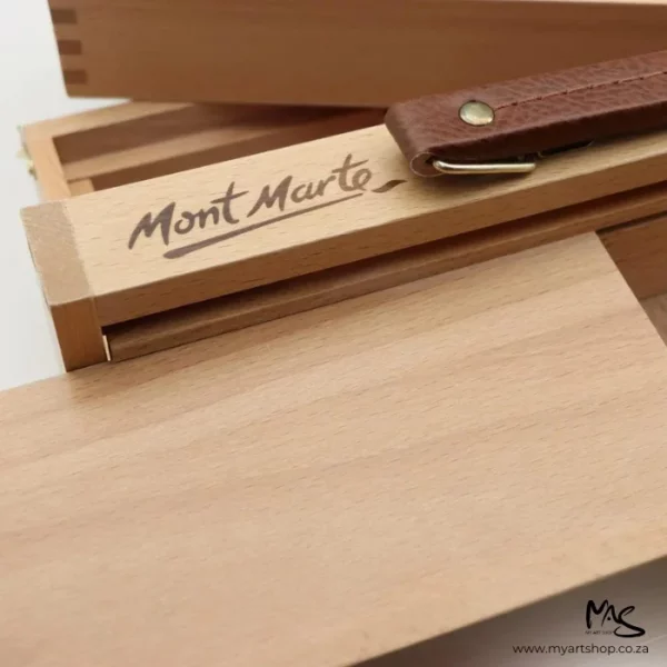 A close up of the handle part of the Mont Marte Signature Multi Purpose Art Box. The handle is brown leather and you can see the mont marte logo burnt into the wood of the box.