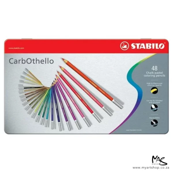 A Stabilo CarbOthello Chalk Pastel Pencil Set of 48 pencils is shown across the center of the frame horizontally. The tin shows an image of the pencils on the front and there is text describing the set. The image is on a white background.