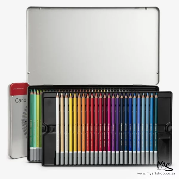 An open set of Stabilo CarbOthello Chalk Pastel Pencil Set of 60 can be seen in the frame. The two trays of pencils are stacked on top of each other and the tin is shown in the background, Only a small portion of the left hand side of the tin can be seen. The lid is facing the top of the frame.
