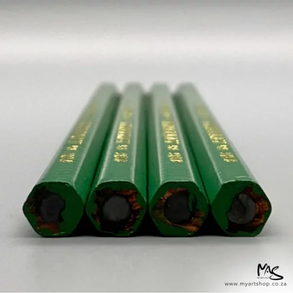 The back of four 9XXB Kimberley Drawing Pencils from the General Pencil Co. are shown in the center of the frame. The image is taken as a close up and the ends of the pencil s in the background are blurred. The pencils have a green wooden barrel and are unsharpened.