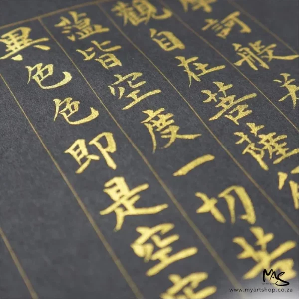 A close up of a piece of black paper that has chinese writing that was written in, using the Gold Kuretake Mica Paste. The text is slightly diagonal across the frame.