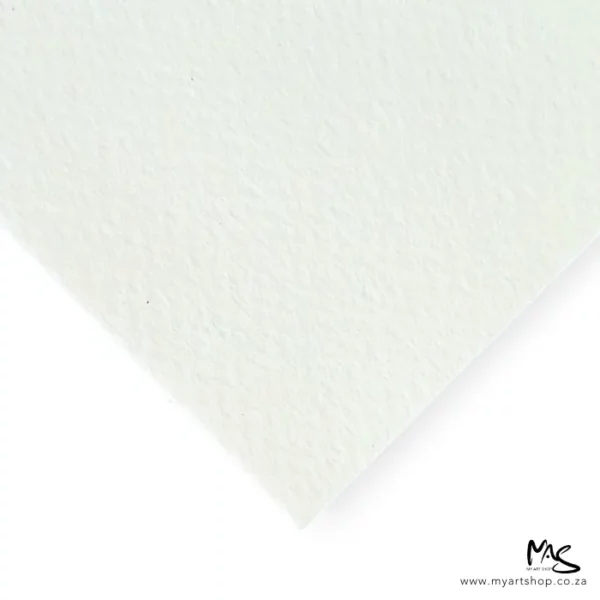 A single sheet of paper from the Prime Art Fabriano Soft Press Pad is seen coming out of the top of the frame. It is a corner of a sheet, and teh corner of the paper is facing the center of the frame. The paper is white and has a slight texture. The image is center of the frame and on a white background.