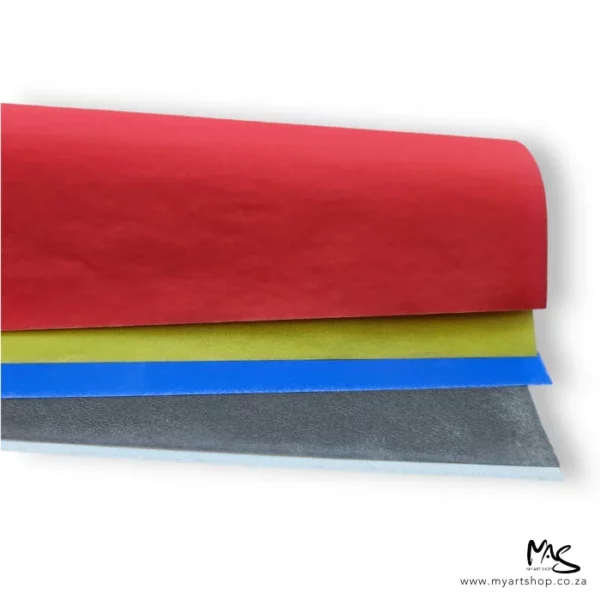 An open Saral Wax Free Transfer Paper Sampler Pack is shown in the image. The papers are loose and different coloured, they are in an open roll which is coming in from the left hand side of the frame. The papers are red, yellow, blue and black. On a white background.