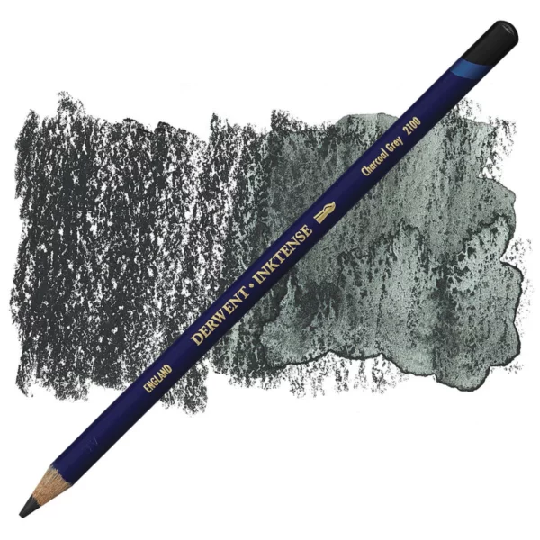 A single Charcoal Grey Derwent Inktense Colour Pencil is shown diagonally across the center of the frame. The pencil is pointing with it's lead facing towards the bottom left hand corner. The barrel of the pencil is blue and the end of the pencil is colour dipped to match the colour of the lead for easy identification. There is text down the barrel of the pencil with the colour name and brand name. There is a colour swatch of the pencil in the background, that runs horizontally across the center of the frame. The image is center of the frame and on a white background.