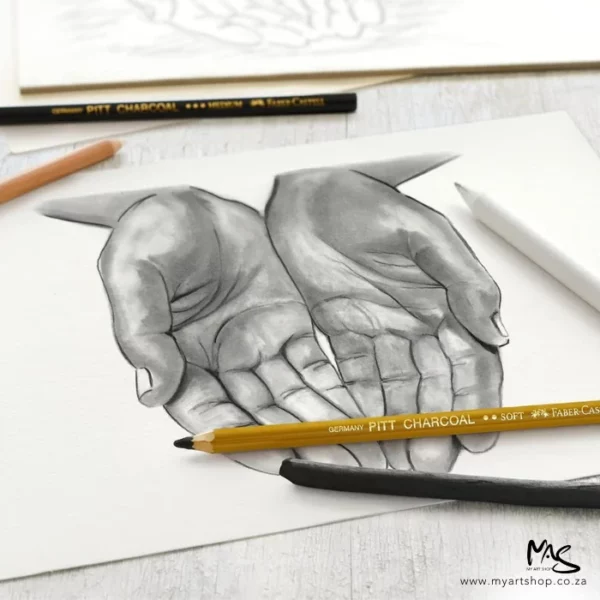 A picture of two open hands is shown in the frame with various pencils laying on top of the drawing. The drawing is showing how the contents of the Faber Castell Charcoal Sketch Set can be used.