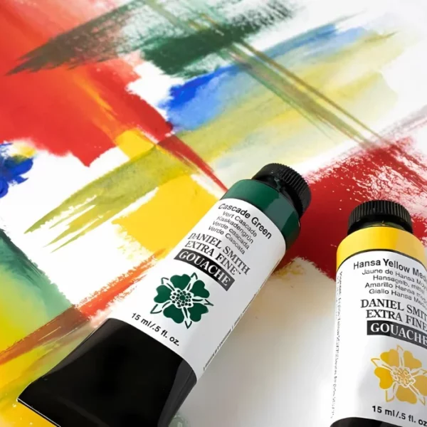 There are tubes of Daniel Smith Extra Fine Gouache Paints shown in the bottom, right hand side of the frame. They are lying on a piece of paper that has been painted with abstract stripes and marks. The painted marks are red, yellow, green and blue. The tubes of paint are green and yellow. The tubes have a black plastic screw on lid, a white tube body that is printed with the paint name and details as well as the Daniel Smith logo. Each tube has a black strip at the end of the tube.