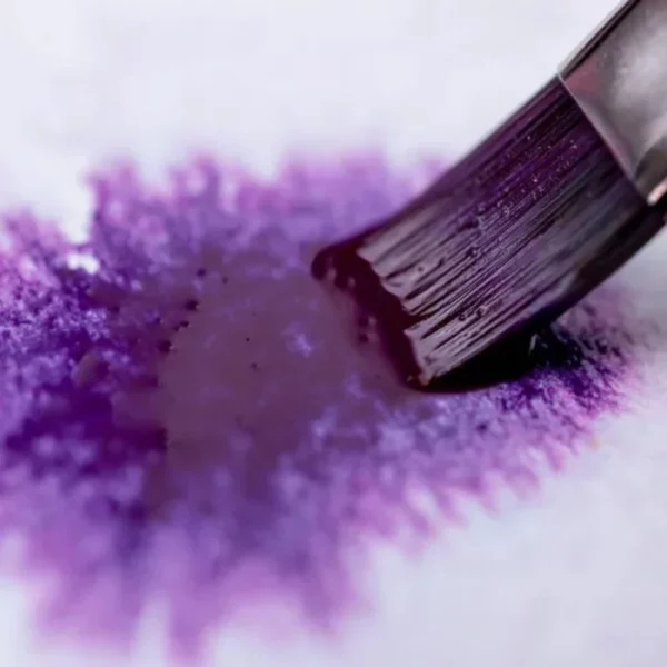 A close up of a paint brush painting a deep purple colour onto a piece of watercolour paper. The paint used is from the Granulating Gansai Tambi Watercolour Set.