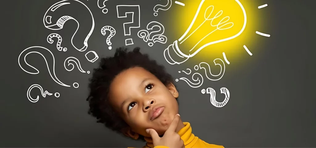 there is a little kid thinking in the centre of the image. he is standing with his head tilted to the left and his hand on his chin and a questioning look on his face and looking up to the right of the image. above him are drawn on a blackboard question marks and a lightbulb that has been coloured in yellow. the little kid is wearing a yellow shirt.