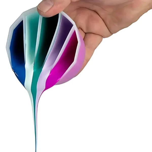 A persons hand is seen coming out of the top right hand side of the frame. They are pouring paint from a Mont Marte Silicone Split Pouring Cup. There are 4 divisions in the cup and each division is holding a different colour. On a white background.