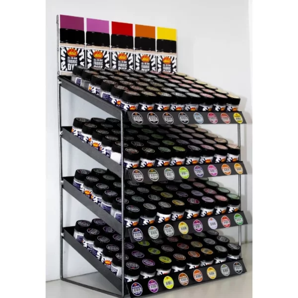 A full, retail display stand of Dala All-In-One Fabric Dye is shown in the frame, The stand is black metal and holds all the dala fabric dyes. Each row has 6 bottles and there are 8 rows per tier, and 4 tiers. The display stand is sitting on a table top surface.