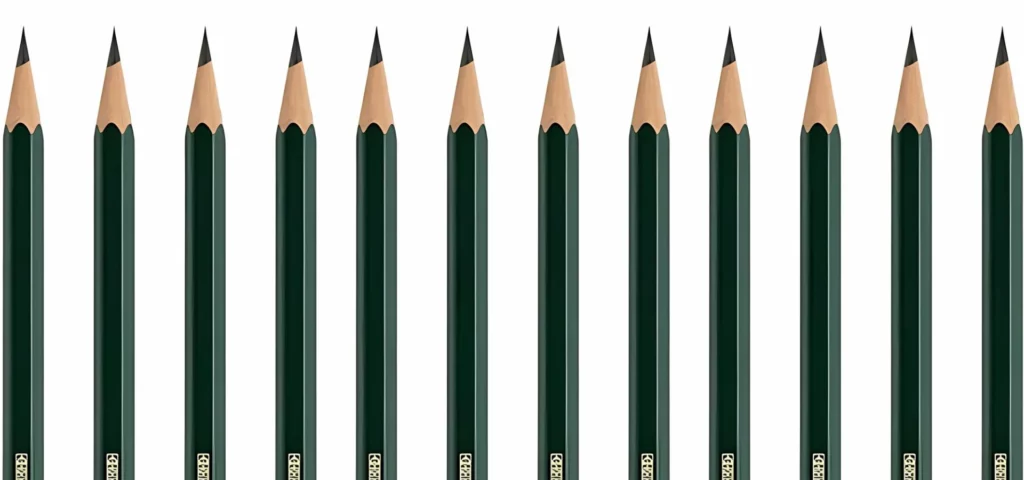 across the whole image faber castell graphite pencils are standing in a row. they are coming up from the bottom of the image. their nibs are facing the top of the image. they have green casing and wood by the nibs that are all very sharp and graphite grey in colour. they have gold writing visable on them. they are equally spaced apart and are on a white background