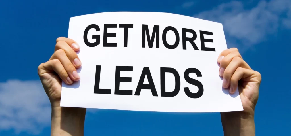 in the center of the image there are a pair of hands holding a big white sign against a blue sky background. the sign says in big bold black letters get more lead. the sun is hitting directly onto the sign