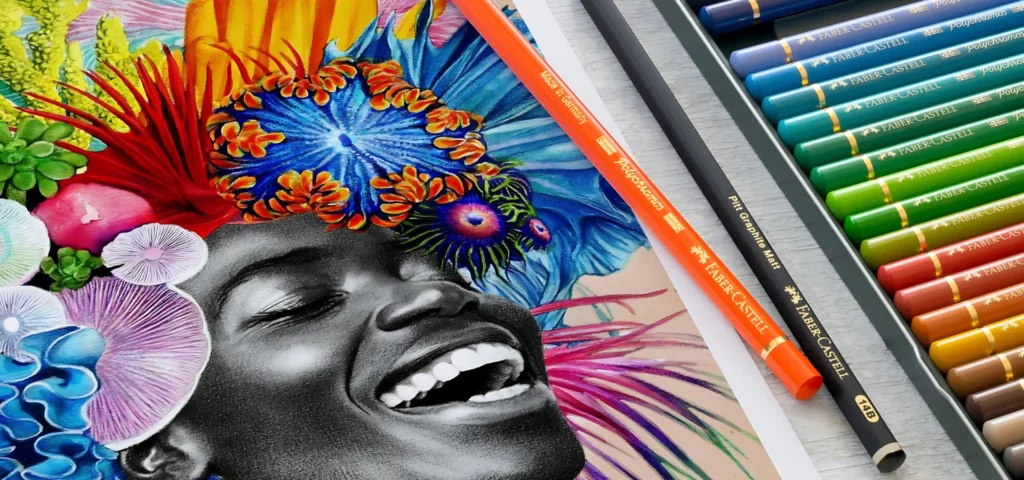 in the centre of the image is the drawing of a woman in black and white using polychromos pencils. around her are flowers drawn in beautiful vibrant colours of blue, orange, yellow, red and green and pink. next to the drawing are two loose pencils. an orange and a black pencil. on the other side of them is a tin of polychromos pencils arranged in a colour order. on a off white table surface.