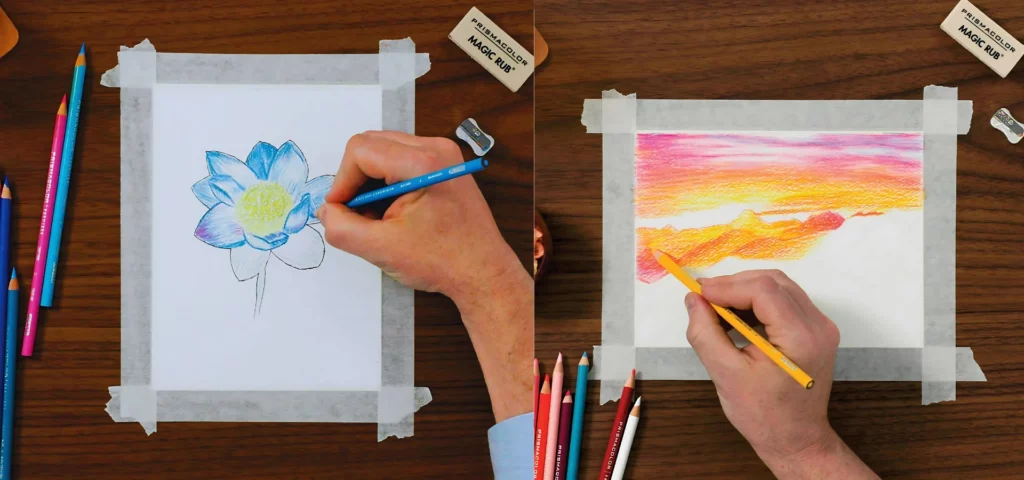 prismacolor pencils are being used in this image. on the left is a person using theor right hand holding a blue prismacolor pencil to draw a flower and color it in. the paper has been taped to the brown wooden table and the pencils are scattered next to it on the left hand side. the right hand side image is a persons right hand holding a yellow prismacolor pencil drawing and coloring a sunset. the paper is taped down ion the wooden table and the pencils are bundled on the left hand side of the page.