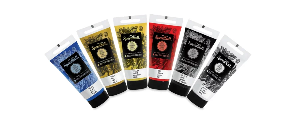 in the center of the image the speedball block inks are layedout in a hald circle shape. they are all standing upright with their lids facing the bottom. their lids are black and the tubes are clear showing what colour is inside of them. the label is a wrap around the whole bottle and is also clear with just black print showing the logo and the details of the product. they are on a white background