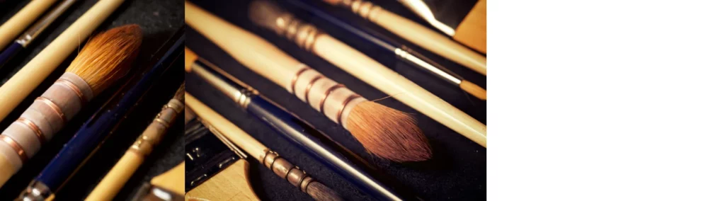 the left hand image is a close up of a mop brush. it has orange haits and a wooden handle. the stems of other brushes are visable in the image. on a dark background. the right hand image is of a close up of a few mop brushes of different sizes. they all have wooden handles. they are on a dark black background