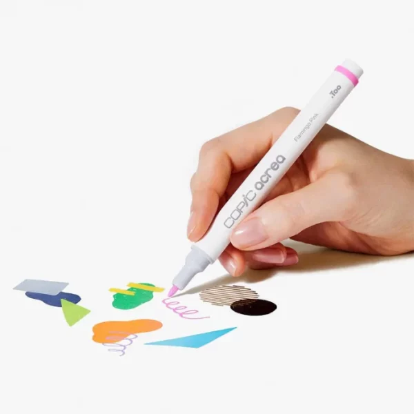 A persons hand is seen coming in from the right hand side of the frame, holding a Copic Acrea Paint Marker. Ther are drawing some test shapes on a piece of paper. The marker is white and has a coloured band around the back of the marker that denotes the colour of the ink. On a white background.