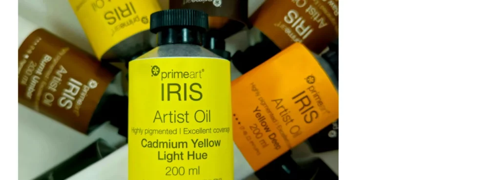 the iris oil paints are stacked on top of eachother. their colour strips are visable showing which colours they are. they are white tubes with black lids on a white background