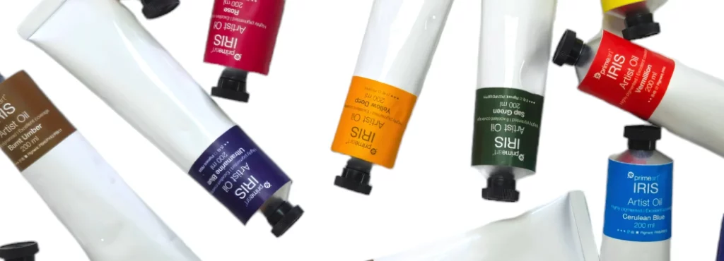 a selection of iris oil paints look like they are falling from the sky. they are all different colours of paint. but have white tubes with black lids and a colour strip at the top showing which colour is inside the tube. on a white background