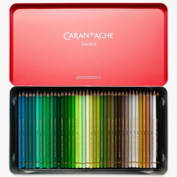 A Set of 120 Caran D'Ache Pablo Coloured Pencils is shown, open, in the center of the frame. You can see the top tray of pencils. Each pencil is lined up next to each other. The pencils have coloured barrels, this denotes the colour of the lead. On a light grey background.