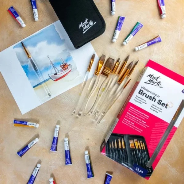 A promotional image for Mont Marte Acrylic Handle Watercolour Brush Set. The brushes are laying on a piece of watercolour paper within the frame. There is a painting of a bird on the paper. The brushes have clear acrylic handles. On a wooden surface.