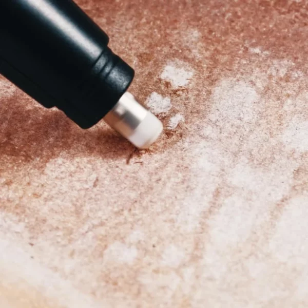 An eraser is shown erasing marks made from a piece of paper that has been coloured using a brown piece of charcoal from the Set of 6 Derwent Tinted Charcoal XL Blocks. It is a close up image and is cut off by the frame.